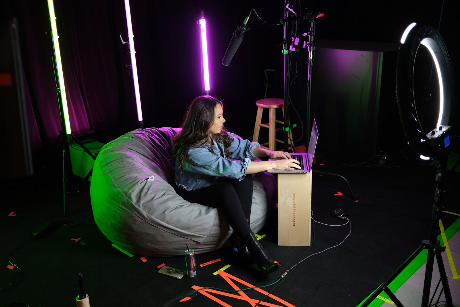 Creator recording on a laptop in a studio lit with purple light